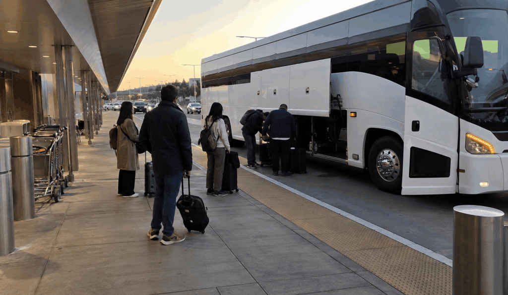 charter bus picking up a group with luggage at oakland airport after baggage claim